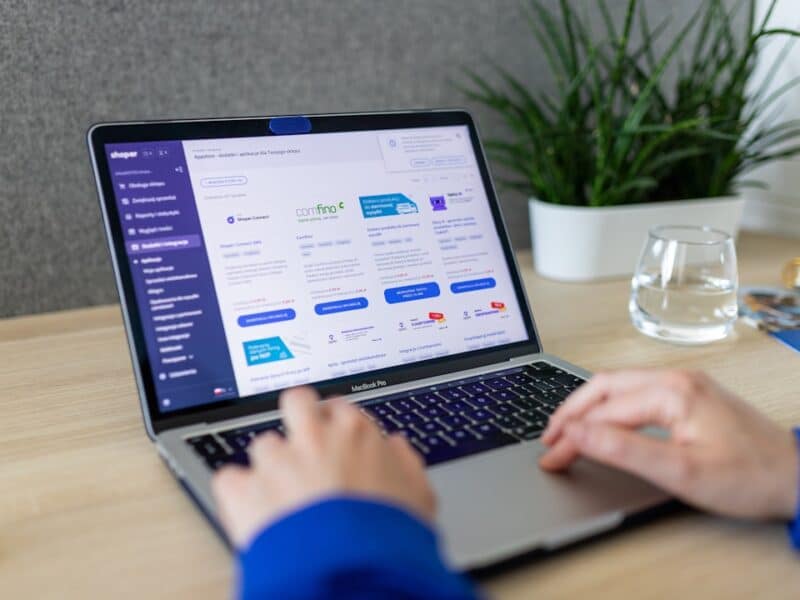 Hands typing on laptop's keyboard. On the computer we can see Shoper AppStore